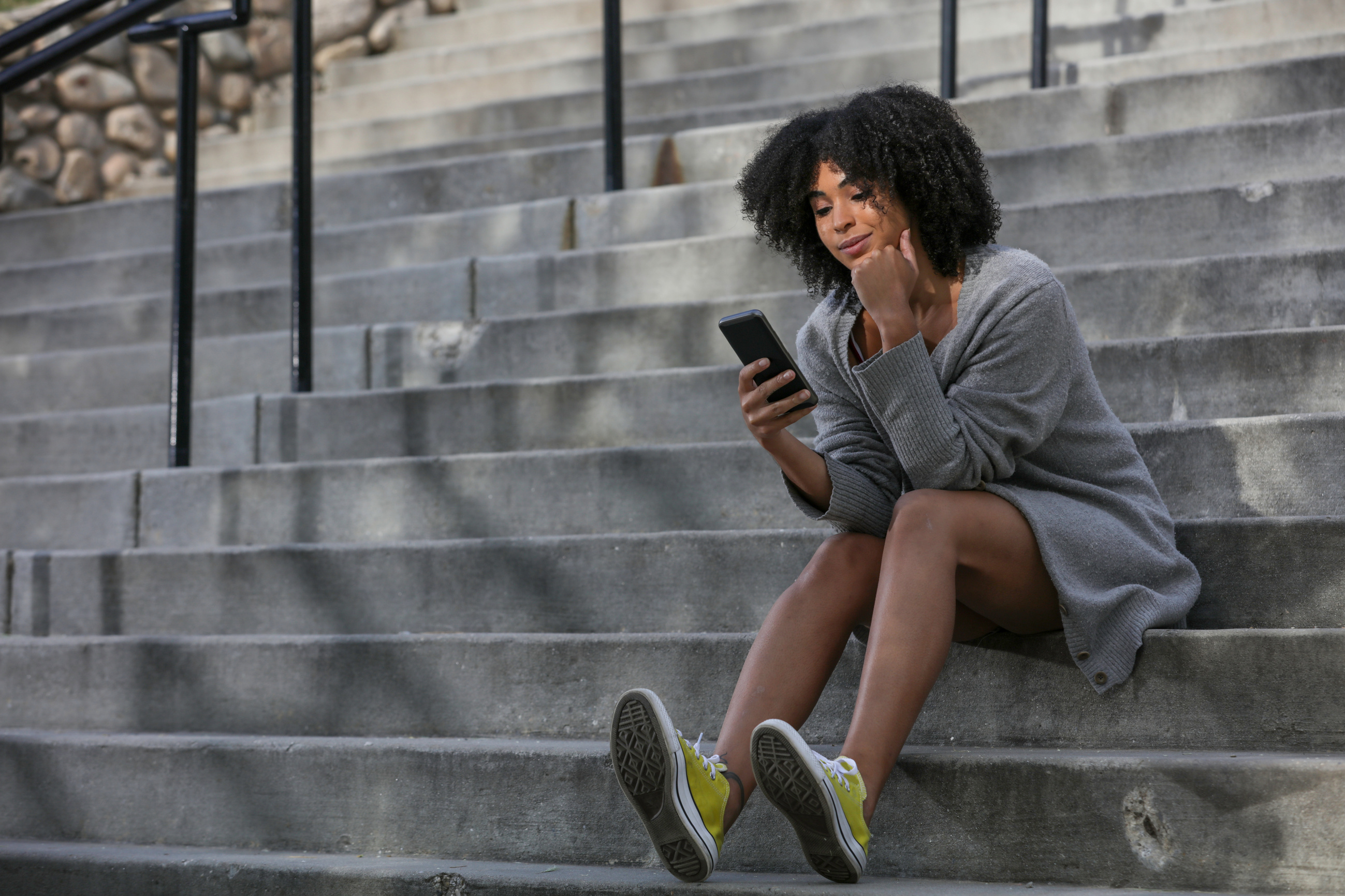 Woman sitting on stairs looking at phone